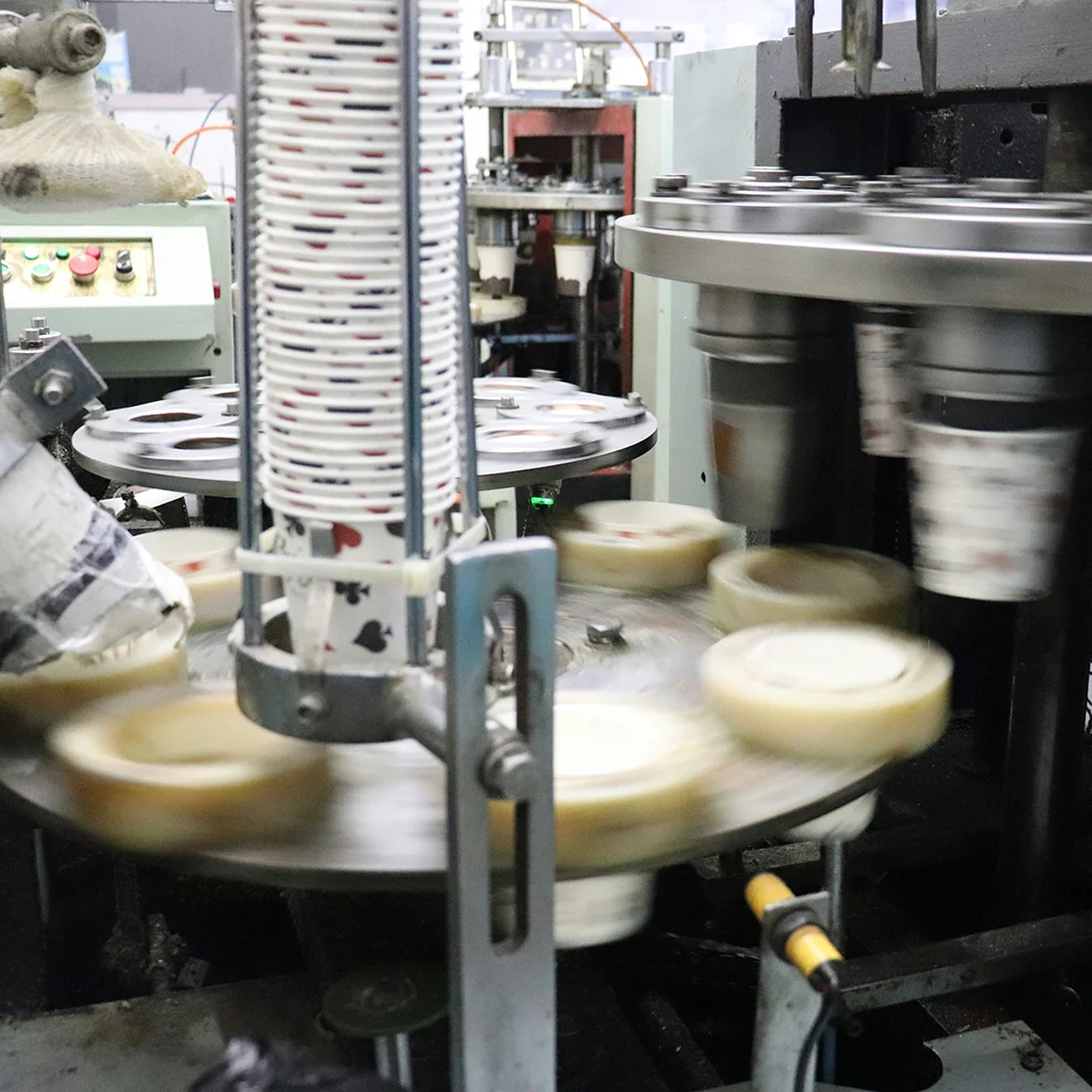 Rotating industrial machinery places paper cups into holders at high speed inside a manufacturing line